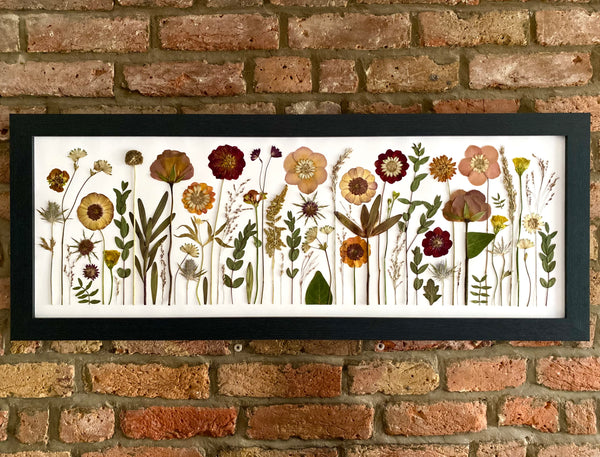 Framed botanical illustration on a brick wall